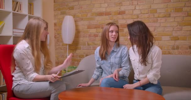 "Closeup", mladý nádherný lesbický pár, který mluví se ženskou reptou o koupi bytu potřásaje si rukama sedícího u stolu uvnitř — Stock video