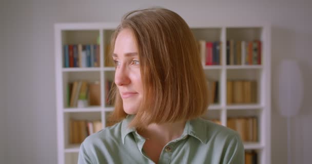 Portrait de caucasienne jeune étudiante sourit joyeusement et rêveur dans la caméra à la maison . — Video