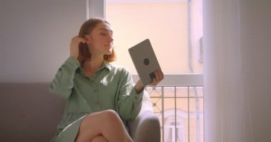 Oturma odasında kanepede oturan tablette güzel selfie'ler çeken genç seksi kız öğrenci portresi.