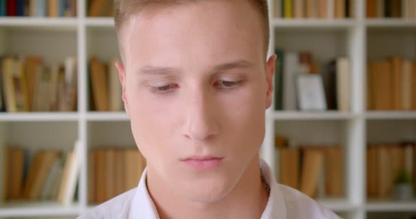 Zbliżenie portret młodego przystojnego kaukaski mężczyzna uczeń patrząc na kamerę w bibliotece kolegium — Wideo stockowe
