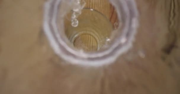 Closeup hajtás a víz öntenek az üveg állva az asztalra — Stock videók