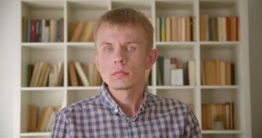 Beyaz kütüphanecinin kitaplıklarda sakin ve utangaç bir şekilde kameraya kamera yla kamera arkası arkası.