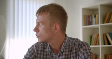 Beyaz kütüphaneciportresi, kitaplıklarda sakin bir bakışla kameraya izlerken.