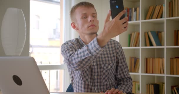 Кавказька бізнесмен сидить перед ноутбуком пошуком мережі на полицях з фону. — стокове відео