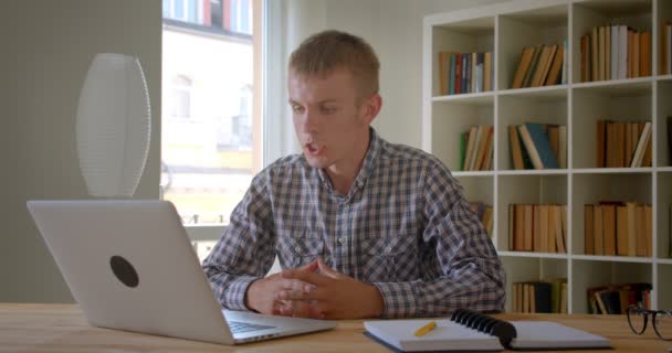 Videochat'te konuşan Kafkas işadamı, kitapraflarında dizüstü bilgisayar kullanarak ciddi ve özenli davranıyor. — Stok video