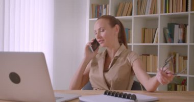 Ofiste rahat olmak cep telefonu konuşurken neşeli kafkas iş kadını eğlendi ve şok olur.
