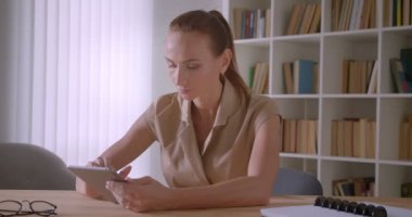 Modern tabletkullanan zarif beyaz iş kadını ofiste neşeli ve memnun.