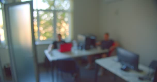 Aufnahmen von Mitarbeitern, die im Büro sitzen und den Laptop drinnen mit unscharfem Fokus benutzen — Stockvideo