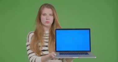Dizüstü bilgisayarı kullanarak ve yeşil izole arka plan ile kameraya mavi ekran gösteren genç güzel kafkas kadın Closeup ateş