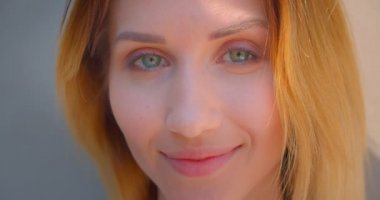 Sarı boylu saçlı genç beyaz kadın yüzünün kameraya baştan çıkarıcı bir şekilde gülümseyen yakın çekim portresi