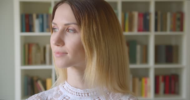 Genç güzel beyaz kadın öğrenci tornalama ve kolej kütüphanesinde kameraya bakarak çekim portre — Stok video