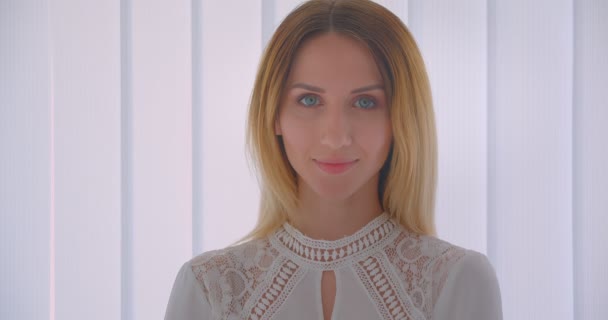 Närbild porträtt av unga ganska kaukasiska affärskvinna leende glatt vände sig till kameran inomhus i ett vitt rum — Stockvideo