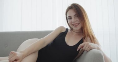 Siyah bodysuit genç baştan çıkarıcı kafkas kadın closeup çekim kanepede gülümseyerek yatıyordu ve kapalı kamera bakarak poz
