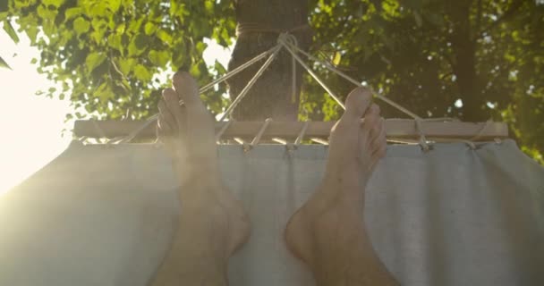 해먹에 누워 있는 남성 다리의 클로즈업 촬영이 야외에서 자연에서 휴식을 취합니다. — 비디오