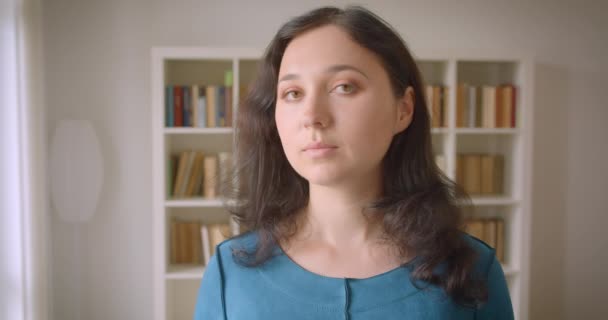 Closeup portrait of young pretty caucasian female student looking at camera smiling happily in the college library indoors — Stock Video