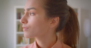 Genç çekici kız öğrenci dönüm ve üniversite kütüphanesinde mutlu bir şekilde gülümseyen kamera bakarak Closeup portre