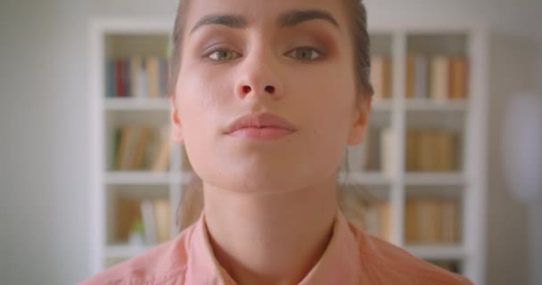 Retrato de cerca de una joven estudiante guapa mirando a la cámara sonriendo felizmente en la biblioteca de la universidad — Vídeo de stock