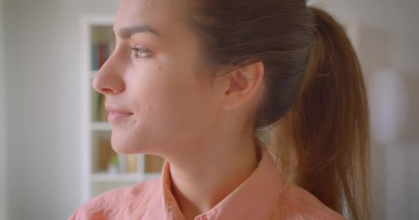 대학 도서관에서 유쾌하게 미소 짓는 카메라를 보고 있는 젊은 예쁜 여학생의 클로즈업 초상화 — 비디오