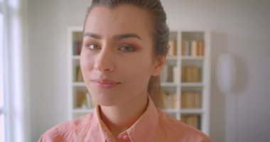 Üniversite kütüphanesinde gülümseyen kameraya bakan genç sevimli kız öğrencinin closeup portresi