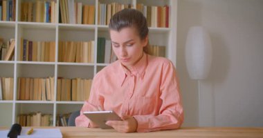 Üniversite kütüphanesinde tablet kullanarak genç çekici kız öğrencinin Closeup portre