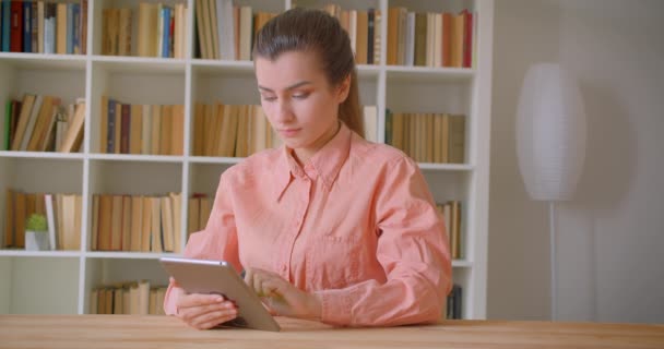 Närbild porträtt av unga attraktiva kvinnliga studenten använder tabletten och visar grön Chroma skärm till kameran i kollegiet biblioteket — Stockvideo