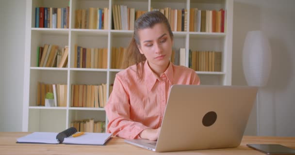 Closeup portrait of young attractive businesswoman working on the laptop in the library indoors — Stock Video