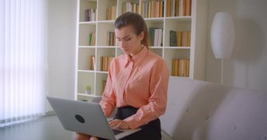 Genç çekici iş kadınının kapalı dairede kanepede oturan dizüstü bilgisayar kullanarak Closeup portre