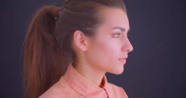 Genç güzel beyaz kadın closeup yan görünüm portre ileriye bakıyor ve kamera gülümseyerek mutlu arka plan gri izole ile dönüyor