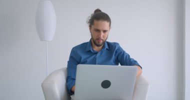 Rahat ve hafif ofiste koltukta oturan dizüstü bilgisayar ile çalışan at kuyruğu ile Progressive freelancer.