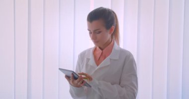 Genç çekici beyaz kadın doktor bir tablet tutan ve kamera kapalı ayakta yeşil renk anahtar ekranı gösteren Closeup portre