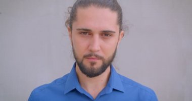 At kuyruğu saatler ile modern freelancer yakın çekim gri duvar arka planda kameraya gülümseyerek.