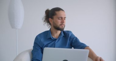 At kuyruklu modern freelancer meşgul ve konsantre olmak ışık ofis koltukta oturan dizüstü bilgisayar ile çalışır.