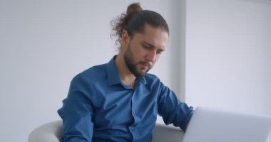 Hafif ofiste koltukta oturan dizüstü bilgisayar ile çalışan at kuyruğu ile Modern freelancer kamera döner ve neşeyle gülümsüyor.