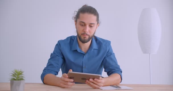 Moderner Geschäftsmann mit Pferdeschwanz schaltet App auf Tablet ein und zeigt horizontalen grünen Chrombildschirm der Kamera im weißen Büro. — Stockvideo