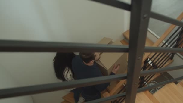 Caucásico pareja sube las escaleras y lleva cajas de cartón en sus manos moviéndose a un nuevo apartamento . — Vídeo de stock