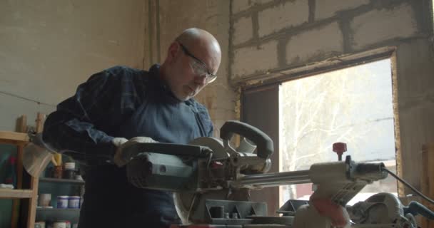 Ανώτερο αρσενικό Μάστερ δουλεύει σε εργοστάσιο ξύλου πιέζοντας το πριόνι κοπής του ξύλου. — Αρχείο Βίντεο