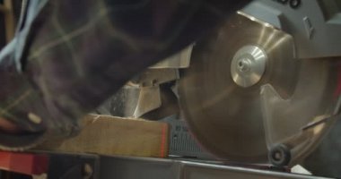 Üretimde küçük kareler içine headsaw ile ahşap oyma erkek kıdemli marangoz ellerinin yakın çekim.