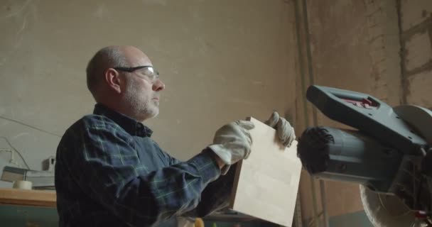 Portrait of senior carpenter checks the quality sanding wooden board in manufacture. — Stock Video