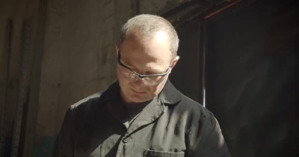 Концентрується портрет ветеранського теслі в захисних окулярах, що працюють на виробництві . — стокове відео