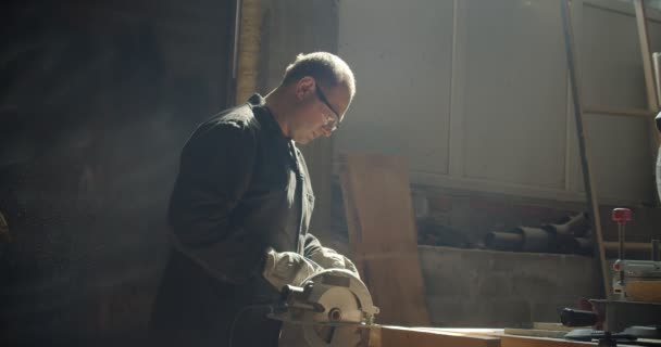 Profile shot of senior male master working at manufacture grinding the wooden board. — Stock Video