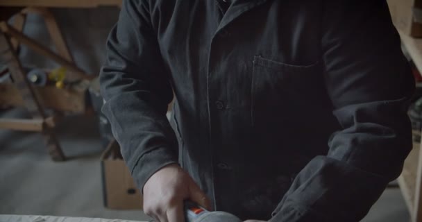 Manos masculinas usando la máquina de pulir para pulir el tablero de madera y hacer patrones en ella en la fábrica de madera . — Vídeos de Stock