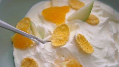 Meyve ve mısır gevreği ile tatlı yoğurt kahvaltı kasesinde bir kaşık daldırma el Closeup makro ateş