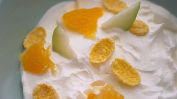 Primer plano macro brote de mano sumergiendo una cuchara en sabroso tazón de desayuno de yogur con frutas y copos de maíz — Vídeos de Stock