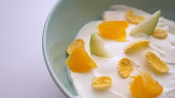 Close-up shoot van smakelijke yoghurt ontbijt Bowl met fruit en cornflakes en lepel wordt gedoopt in het — Stockvideo