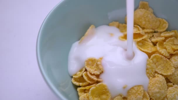 Closeup lő a tej, hogy öntötte a reggeli tálba a kukoricapehely — Stock videók
