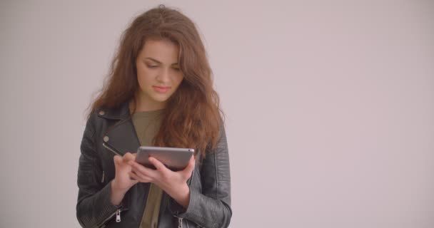 Brunette model werken met Tablet wordt bezet glimlacht in camera geïsoleerd op witte achtergrond. — Stockvideo