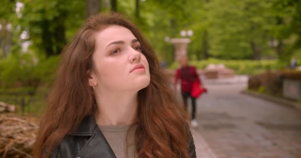 Close-up shot van Kaukasische brunette vrouw zittend in het groene park kijken naar de schoonheid van de natuur. — Stockvideo