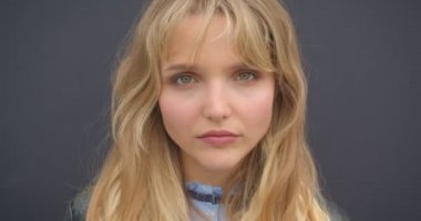 Yeşil gözlü sevimli sarışın öğrencinin yakın çekim siyah duvar arka planda kamera içine dikkatle ve ciddiyetle izler.