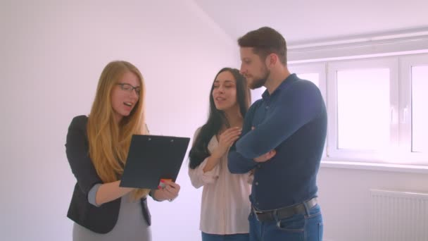 若い白人のカップルにアパートを示し、説明する女性白人の不動産業者. — ストック動画