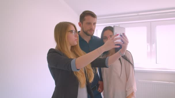 Ingatlanügynök bemutató fiatal kaukázusi pár a lakás eladó bizonyítja a lehetőségeket tabletta. — Stock videók